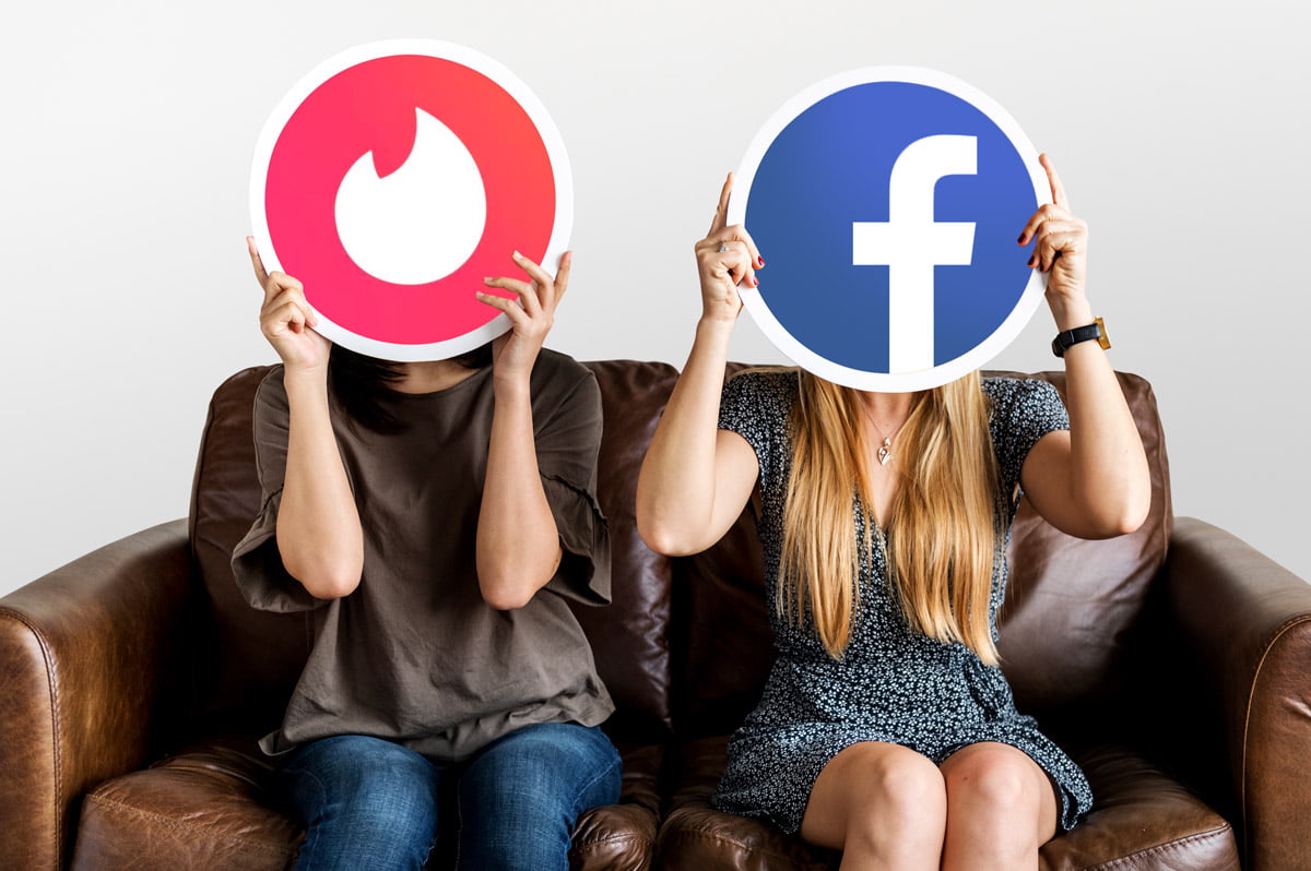 Mujeres con dos logotipos de redes sociales horizontales y verticales (tinder y facebook) tapándose la cara para hablar sobre su definición, características y empleo en la estrategia digital de cualquier negocio.