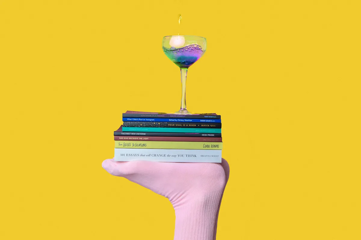 Mesita con forma de mano sujetando una serie de libros de marketing digital coronados con un cóctel sobre un fondo amarillo corporativo del color garajedoce.
